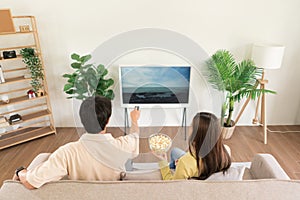 Relaxation concept, Couple holding remote control to changing channel and eating popcorn together