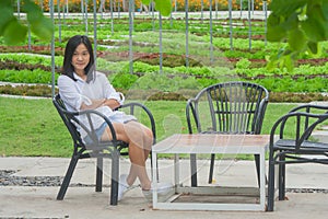 Relaxation Concept : Woman relaxing on wooden chair at outdoor garden surrounded green natural.