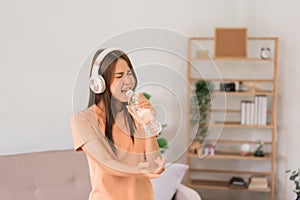 Relaxation concept, Young woman wear headphone listening music and hold water bottle to singing