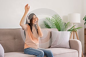 Relaxation concept, Young woman wears headphone to listening music and dance while sitting on couch