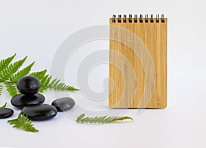 Relaxation spa treatment concept. Fern leaves, spa stones and a notebook with space for text