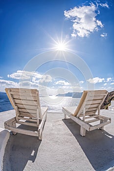 Relaxation on sunbeds against sunset in Oia village, Santorini island, Greece