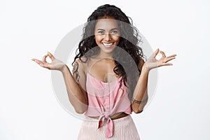 Relaxation, yoga and happiness concept. Attractive curly african-american tattooed girl in stylish pink top smiling