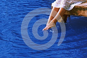 Relaxation. Young woman wets feet in water. Sea, ocean, travel