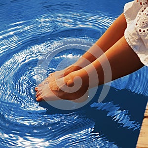 Relaxation. Young woman wets feet in water. Sea, ocean, travel