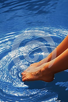 Relaxation. Young woman wets feet in water. Sea, ocean, travel