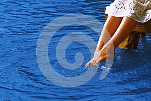 Relaxation. Young woman wets feet in water. Sea, ocean, travel