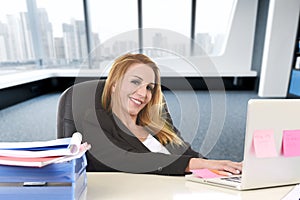 Relaxed 40s woman with blond hair smiling confident sitting on office chair working at laptop computer