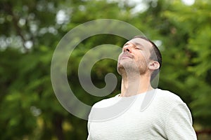 Relaxed adult man breathing fresh air in a forest