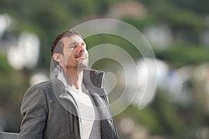 Relaxed adult man breathing fresh air outdoors in winter