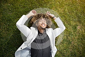 Relaxed african american man entrepreneur lying on green grass on lawn and relaxing during break from work in park