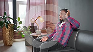 Relaxed african american man listening music in headphones using tablet.