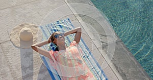 Relaxed african american woman in sunglasses sunbathing on towel by pool, copy space, in slow motion