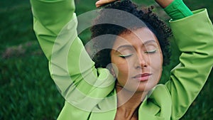 Relaxed african lady dancing sensually on nature with closed eyes close up.