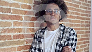 Relaxed Afro-American young man looking at camera while leaning on stone wall at home