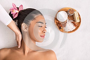 Relaxed asian woman enjoying neck massage with natural ingredients cosmetics at spa