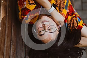 Relaxed Asian woman listening to music on headphones while lying on park bench