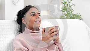 Relaxed Asian woman smiling drinking coffee tea enjoy weekend leisure at home white room closeup