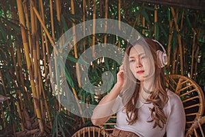 Relaxed asian woman with wireless headphones, listening to meditation music and smiling with pleasure. Joyful young girl wears