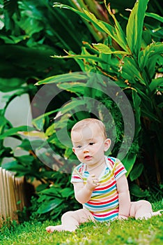 Relaxed baby enjoying the sensation of noticing the freshness of the grass on his bare feet