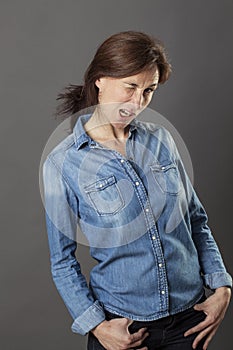 Relaxed beautiful middle aged woman winking with hands in pockets