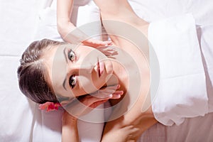 Relaxed beautiful woman lying on her back and looking at camera during massage treatment closeup portrait