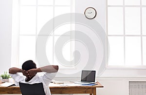 Relaxed black businessman with laptop in modern white office