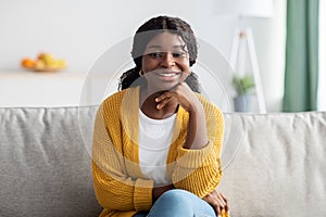 Relaxed black lady in casual sitting on couch at home