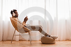 Relaxed Black Man In Headset Using Phone Listening Audiobook Indoor