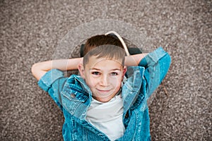 Relaxed boy lying on ground, top view.