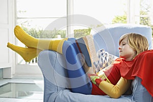 Relaxed Boy In Superman Costume Reading