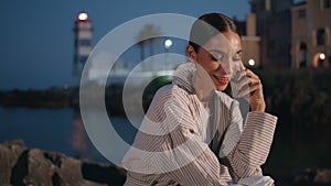 Relaxed brunette speaking mobile phone at evening waterfront close up.