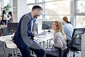 Relaxed business executive having pleasant conversation with female employee in the office.