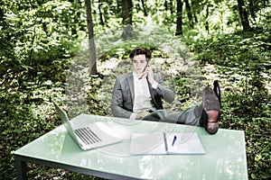 Relaxed business man in suit in green park at office desk talk at mobile phone succesful job done. Business concept.