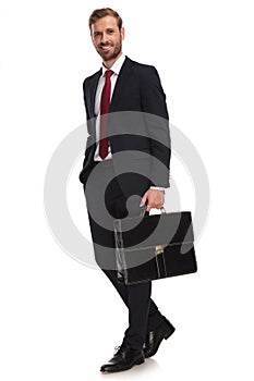 Relaxed businessman with briefacase walks to side to work