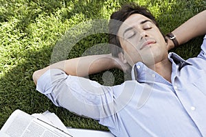 Relaxed Businessman Lying On Grass At Park photo