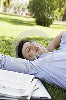 Relaxed Businessman Resting On Grass At Park