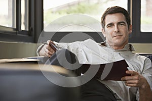 Relaxed Businessman Sitting On Sofa With Folder