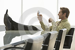 Relaxed Businessman Text Messaging On Cell Phone In Conference R