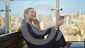 Relaxed businesswoman calling smartphone on glass terrace. Smiling manager rest