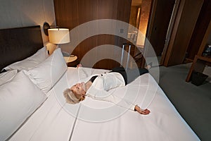 Relaxed businesswoman chilling on her comfortable hotel bed