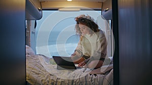 Relaxed businesswoman looking laptop screen sitting trailer bed at twilight.