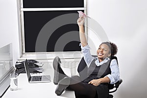 Relaxed businesswoman throwing paper airplane in office