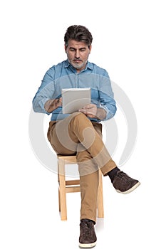 Relaxed casual man reading and writing on his tablet