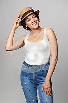 Relaxed casual mixed race woman in jeans and white tank top wearing canotier straw hat