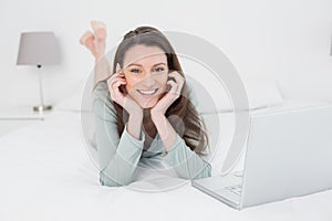 Relajado mujer sonriente computadora portátil en una cama 