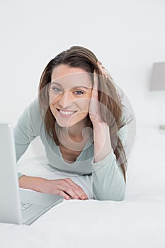 Relaxed casual smiling woman using laptop in bed