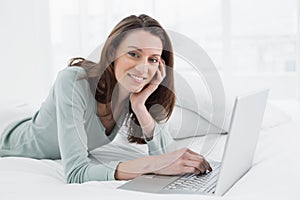 Relaxed casual smiling woman using laptop in bed