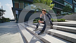 Relaxed ceo talking mobile phone sitting urban stairs with coffee cup zoom in.