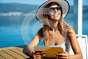 Relaxed and cheerful. Work and vacation. Outdoor portrait of happy young woman using tablet